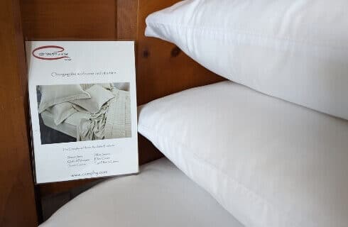 A bed with white sheets and a sign about the sheets