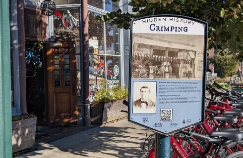A cycling shop with a number of bicycles outside the shop, with a sign that says Hidden History Crimping, and a story about the Crimper King of Port Townsend.