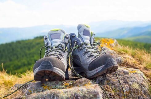 a pair of hiking boots on a rock with mountains in the background