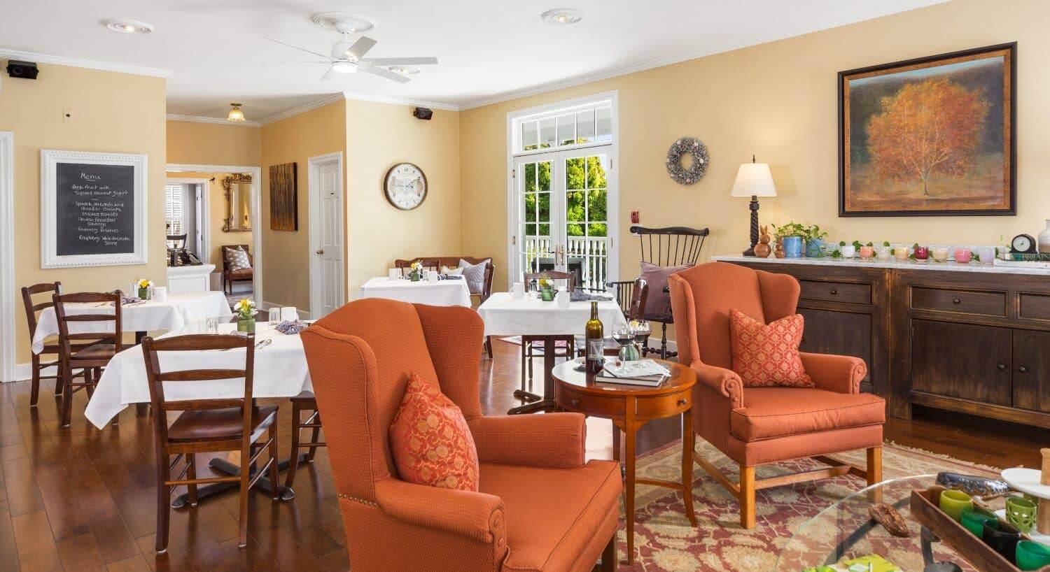 A dining room and sitting area in a room with yellow walls and white trim